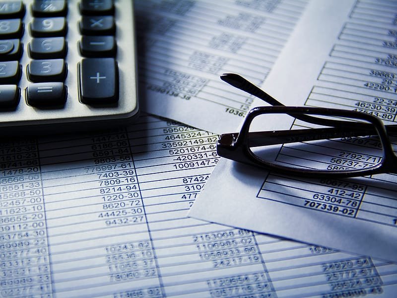 A calculator and reading glasses on printed financial figures